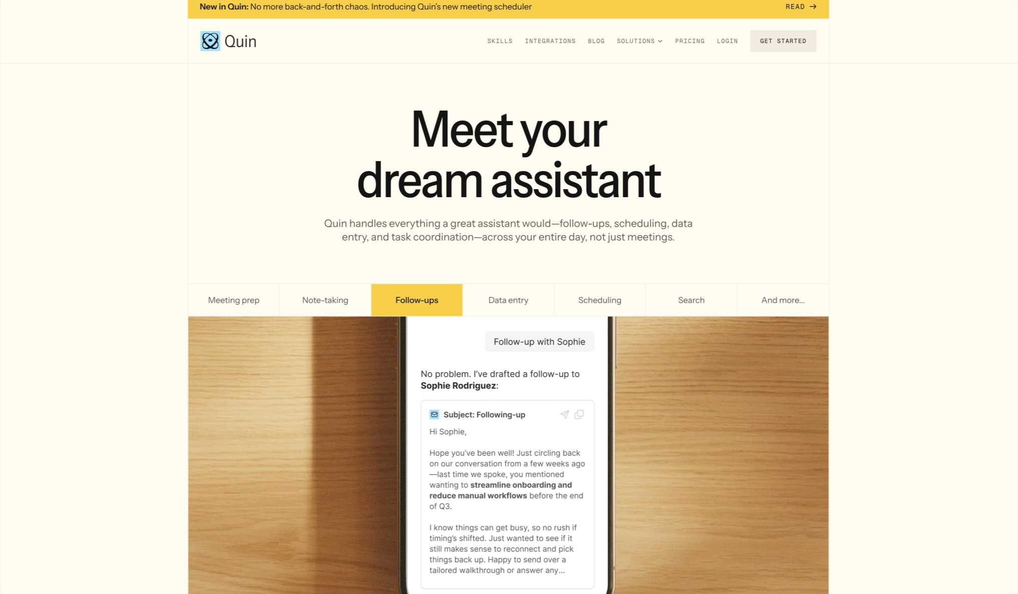 Hero section with large serif headline 'Meet your dream assistant', yellow announcement banner, navigation bar, and tabbed feature showcase with phone mockup on wood surface. captured website design